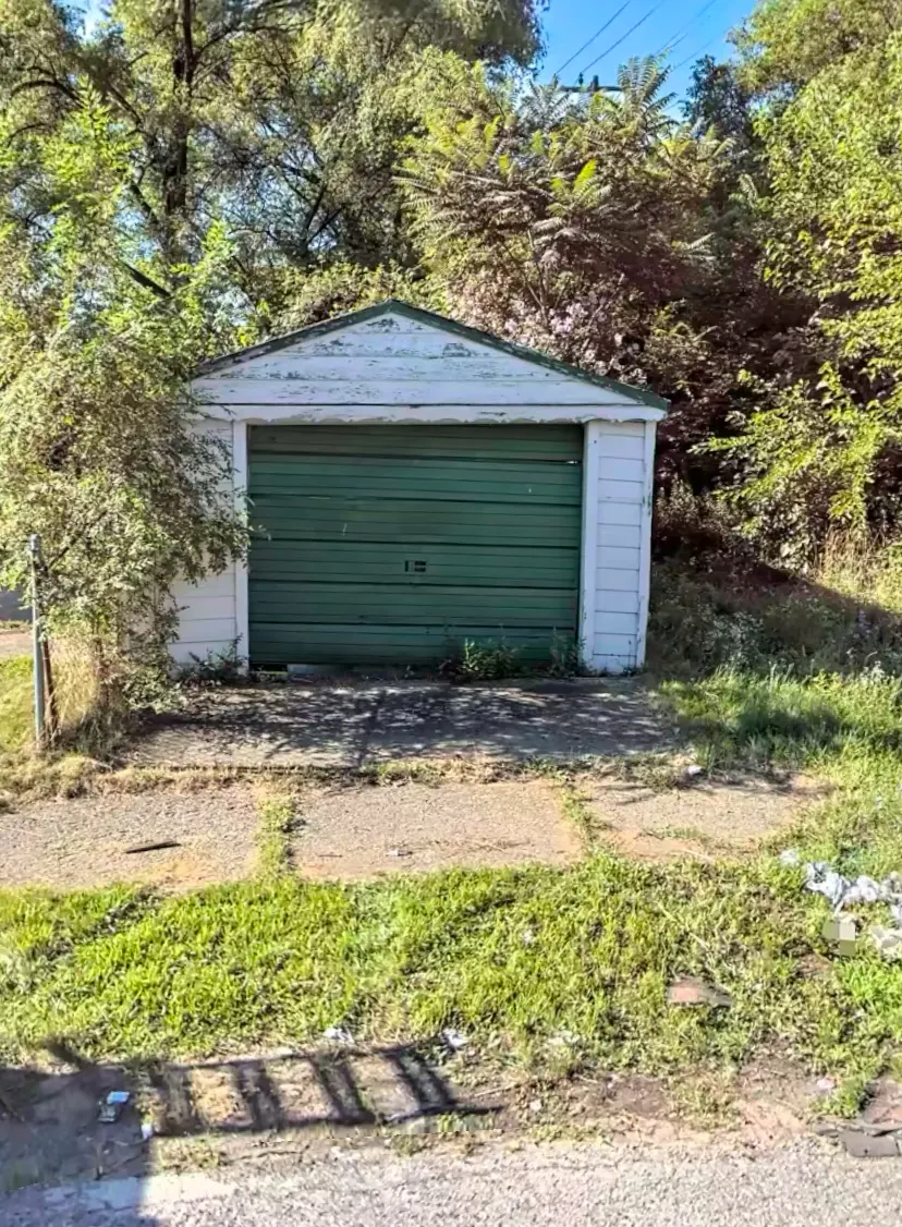 Old detached garage with green door before demolition